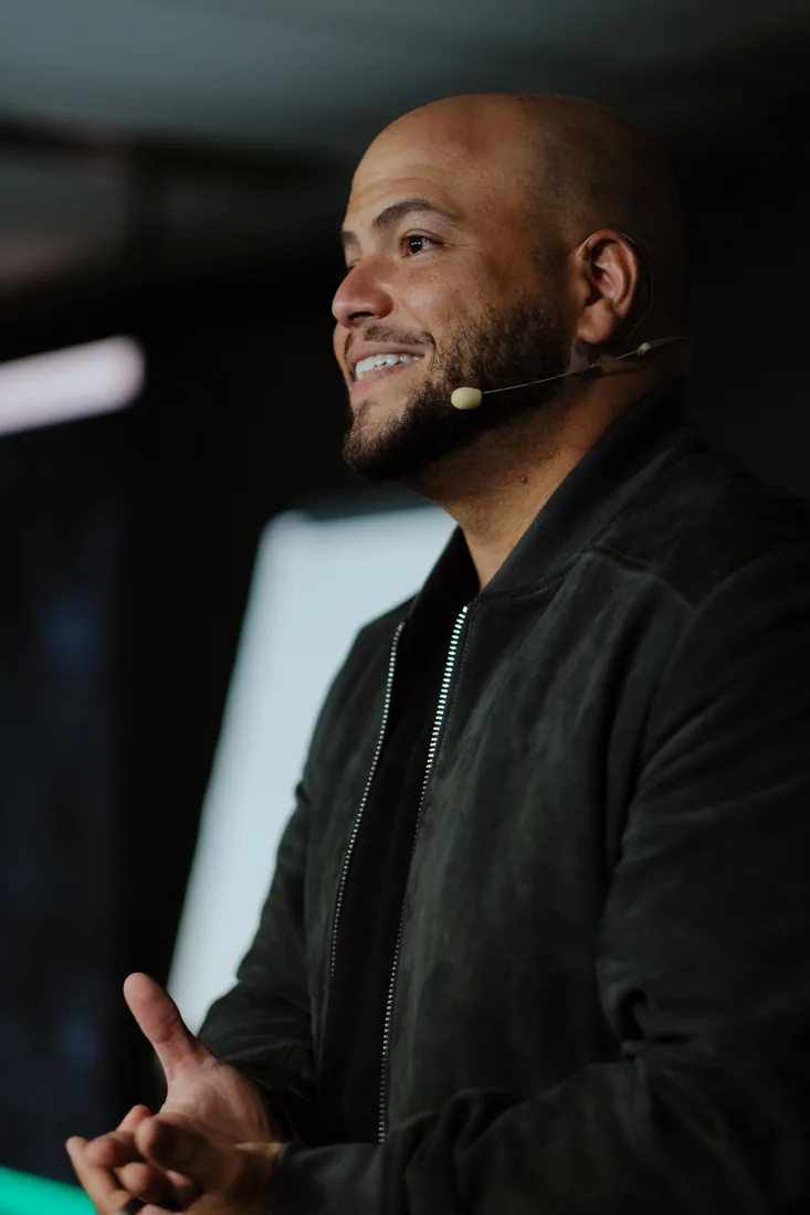Victor Damásio de microfone headset, sorrindo enquanto fala